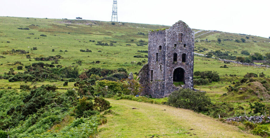 Old ruined Cornish mine in a green, hilly area.