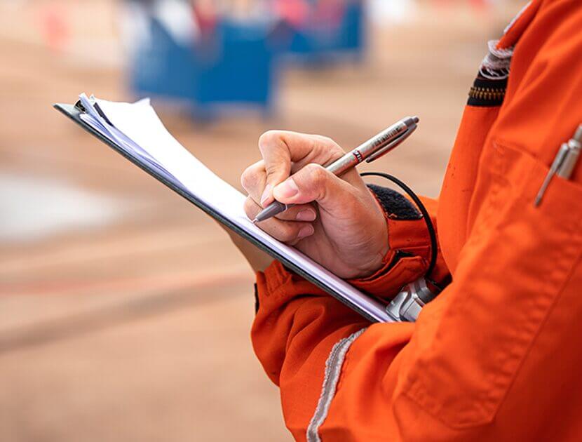 A workman writing on a clipboard on a building site